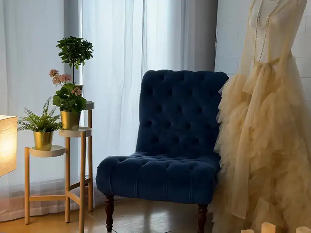 Stylish blue velvet chair with floral decor in a bright, modern vanity studio setting.
